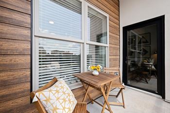 A wooden chair with a cushion is placed in front of a window with blinds.at Converge KC Uptown, Missouri